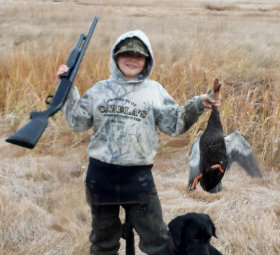 Young hunter holds up the duck he shot