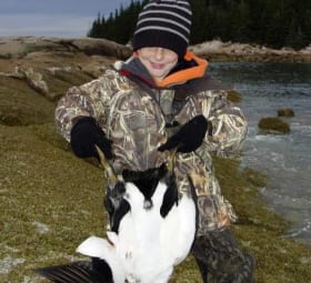 Young kid holding up what he hunted
